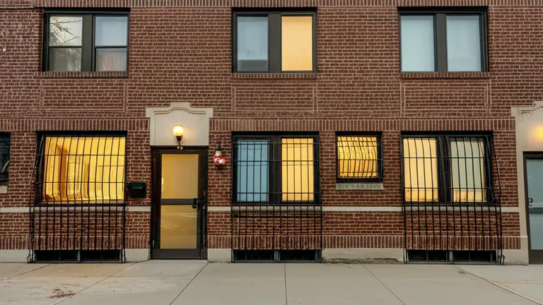 Chicago residential apartment building exterior at dusk showing ground-floor windows with steel security bars installed