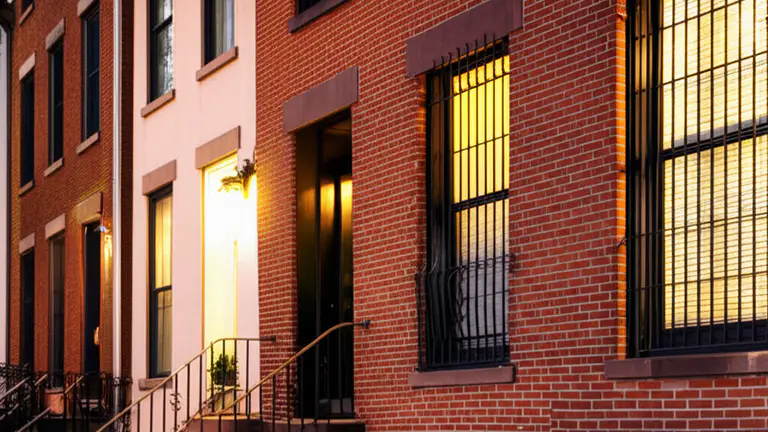 Historic American townhouse row at dusk showing varied decorative iron window security grille styles on ground floor