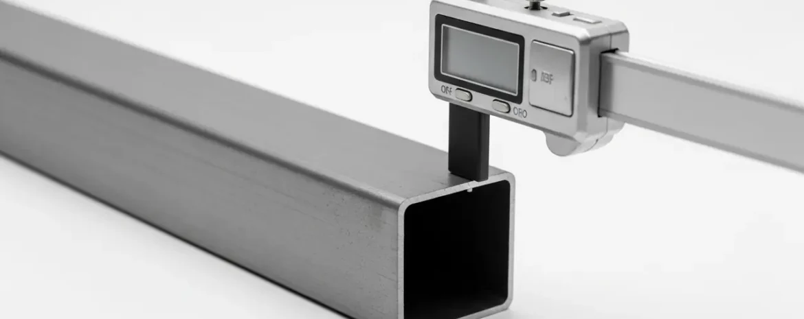 Digital caliper measuring the outer width of a square hollow metal tube (aluminum).